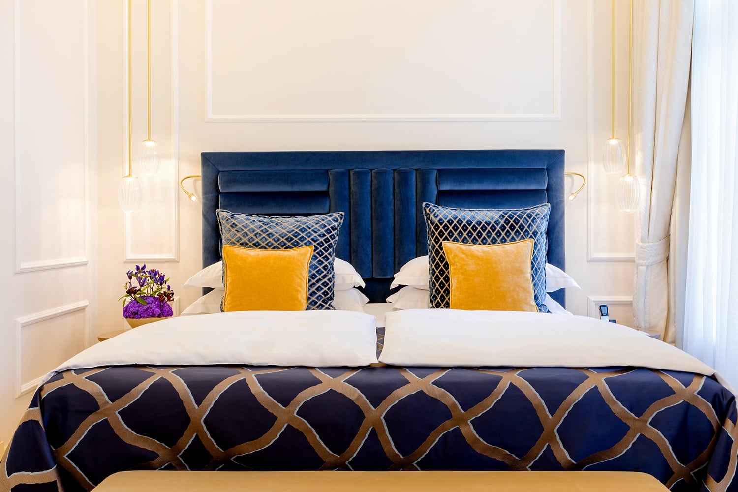 Blick auf ein Doppelbett mit blauen und gelben Zierkissen in der Hotel Suite Köln