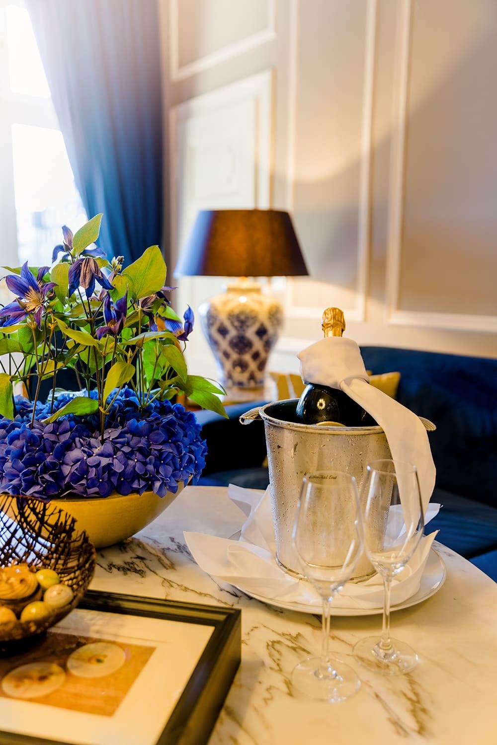 Auf einem Marmortisch steht eine Blumenschale und ein Champagnerkühler mit zwei Gläsern