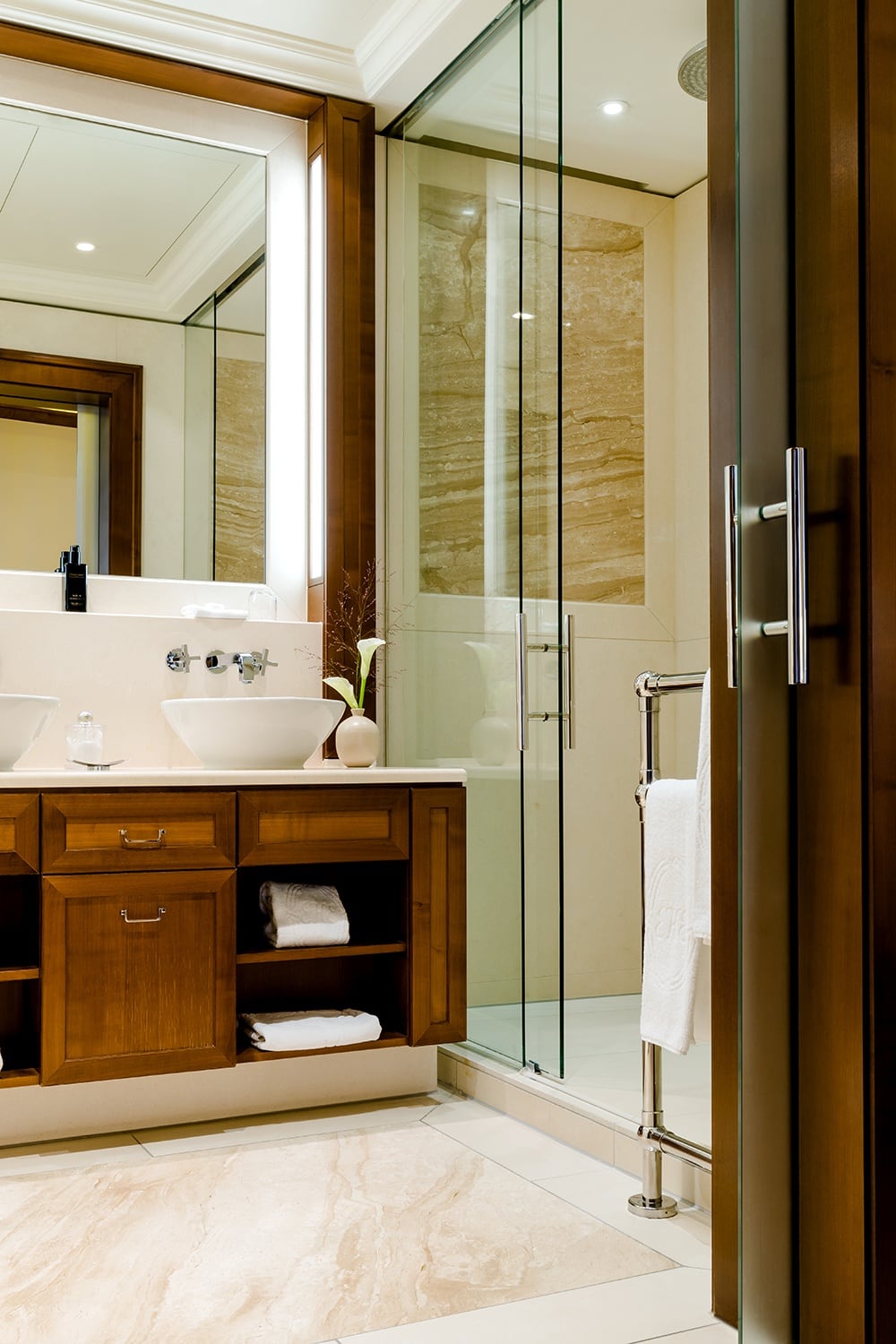 Blick in ein Badezimmer mit Glasdusche und zwei Waschbecken vor einem großen Spiegel