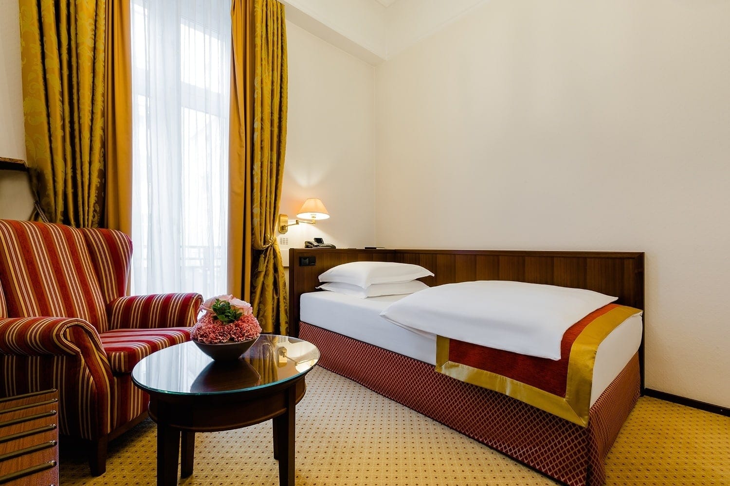 Hotelzimmer in Köln mit einem Einzelbett und einem rot gestreiften Sessel