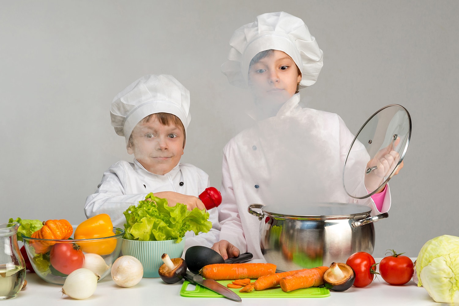 Zwei Kinder in Kochkleidung öffnen ein Topf